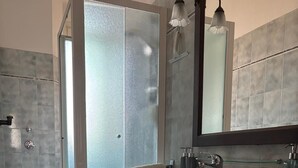 Une salle de bain moderne avec une douche à parois de verre, un lavabo blanc et un meuble-lavabo en bois foncé.