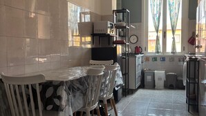 Une cuisine équipée d’une table et de chaises, d’un réfrigérateur, d’un évier et d’une fenêtre avec des rideaux.