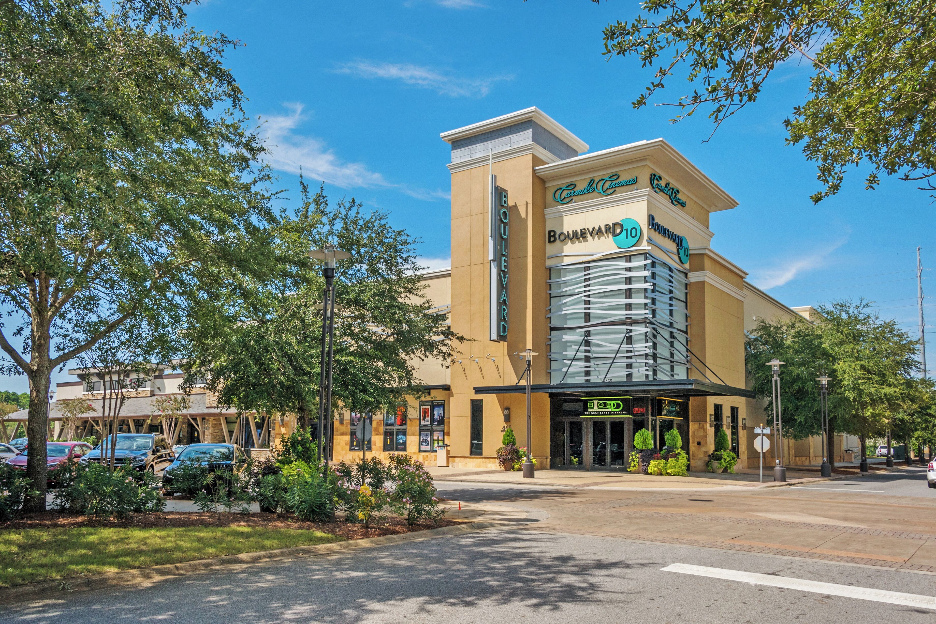 A hotel with a modern facade, a prominent entrance, and a parking lot with several cars.