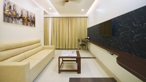 A modern living room with a sofa, a table, a ceiling fan, and a large window with curtains.