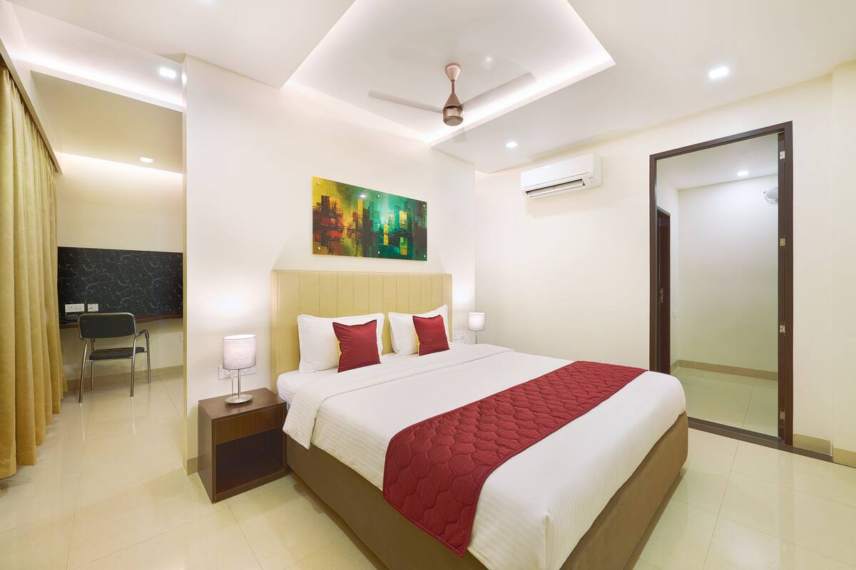 A modern hotel room with a large bed, a desk, and a chair.