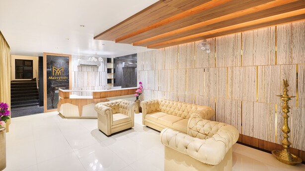 A modern hotel lobby with a reception desk, plush seating, and a marble wall.
