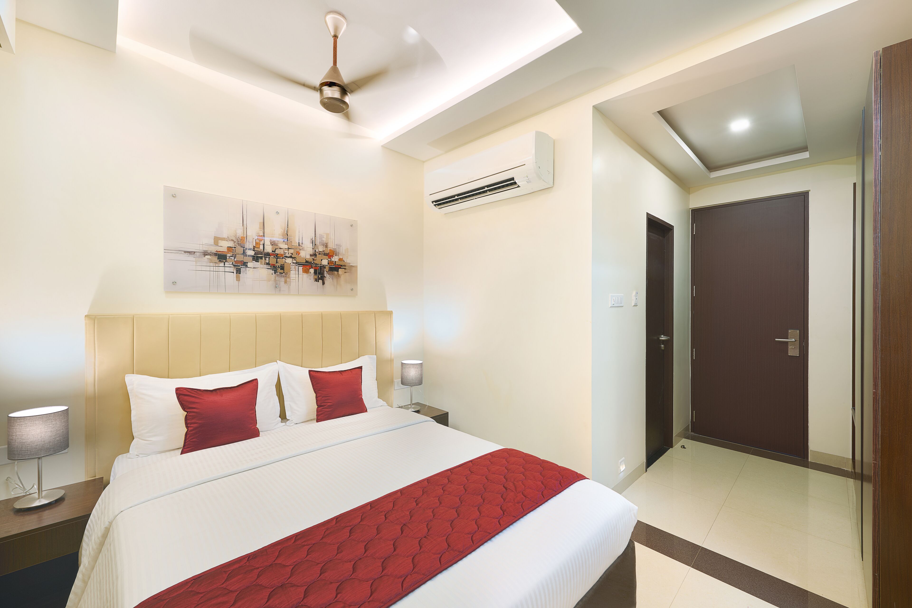 Une chambre d’hôtel moderne dotée d’un grand lit, d’un ventilateur de plafond, d’un climatiseur et d’une porte donnant sur une autre chambre.