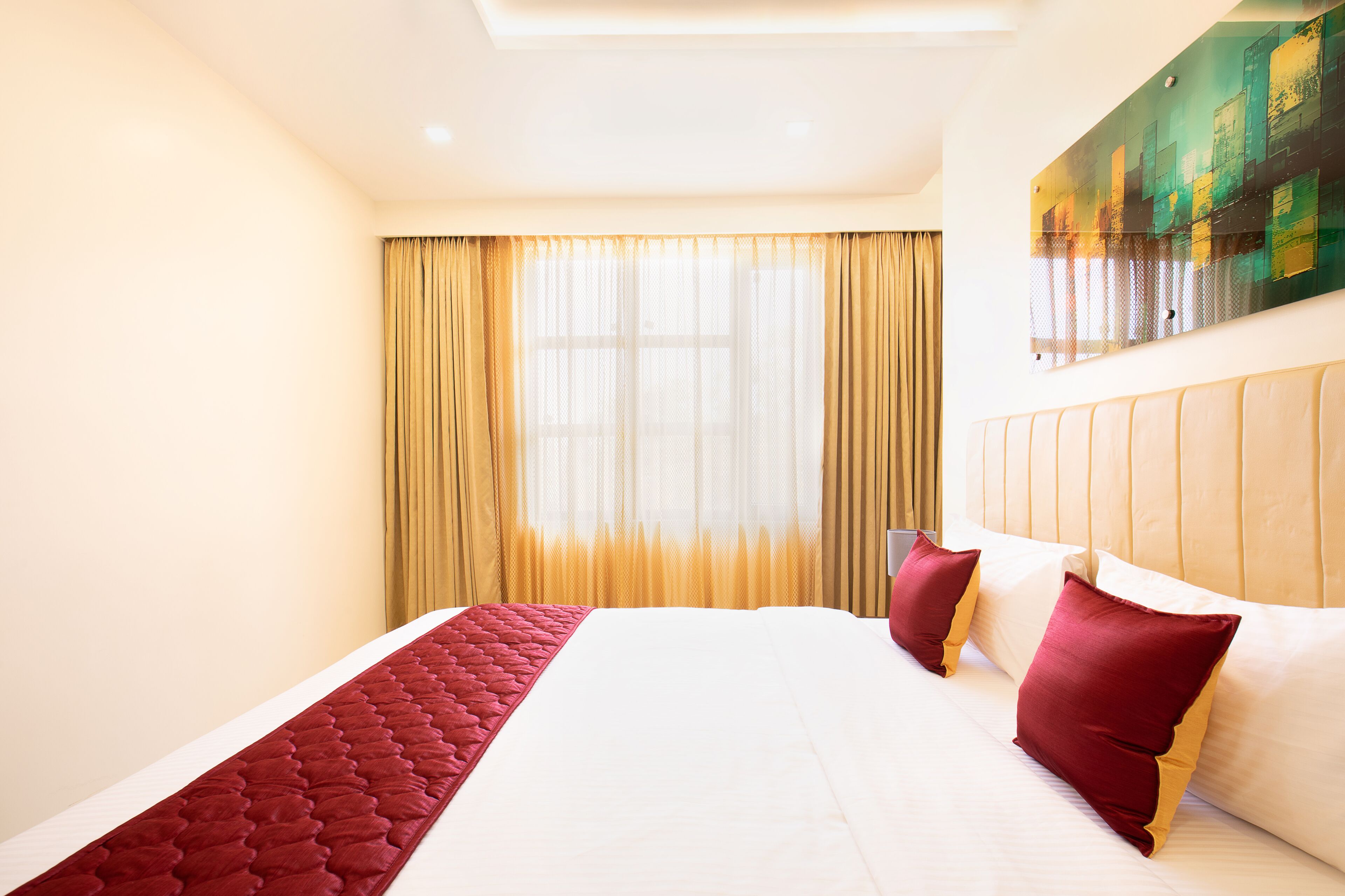 A hotel room with a large bed, a headboard, and a window with curtains.