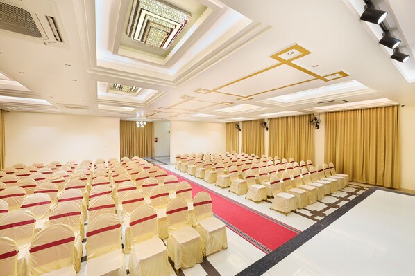A conference room with rows of chairs, a red carpet, and a ceiling with recessed lighting and skylights.