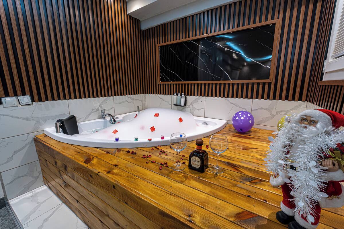 A modern bathroom with a wooden vanity, a marble sink, and a large mirror.