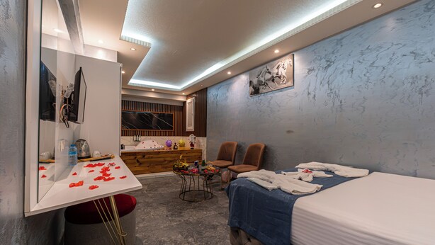 A modern hotel room with a large bed, a vanity with a mirror, a small table with toiletries, and two chairs. - Stay Suite Hotel (Eyup)