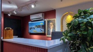 A reception desk with a digital screen, a framed portrait, and a potted plant. - Stay Suite Hotel (Eyup)