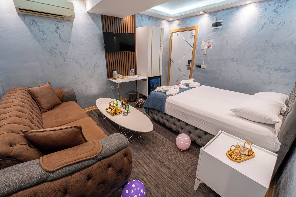 A modern hotel room with a sofa, a bed, a small table, and a TV.