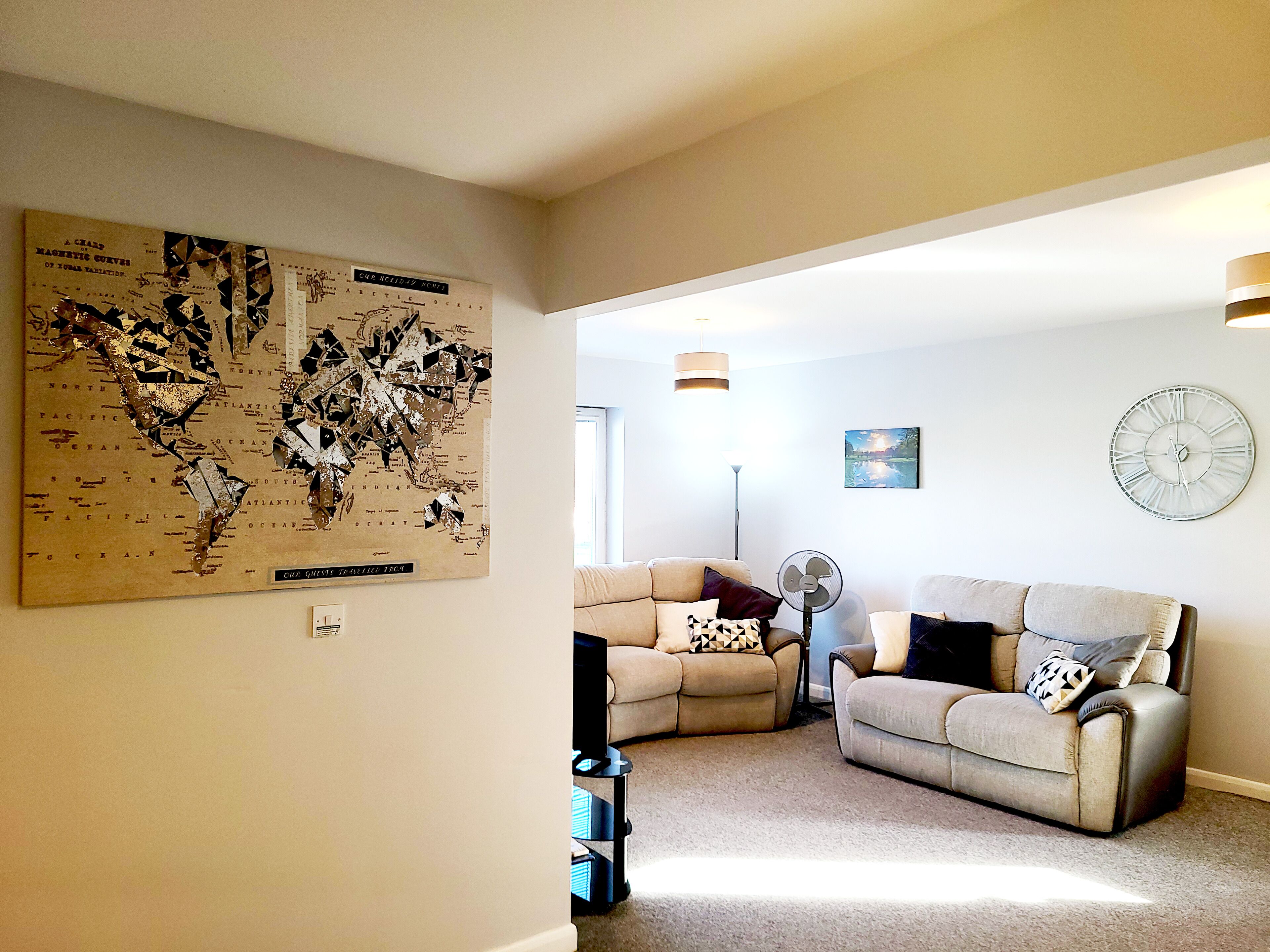 A living room with a large map on the wall, two sofas, a floor lamp, and a clock.