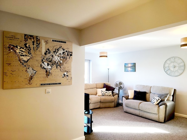 A living room with a large map on the wall, two sofas, a floor lamp, and a clock.