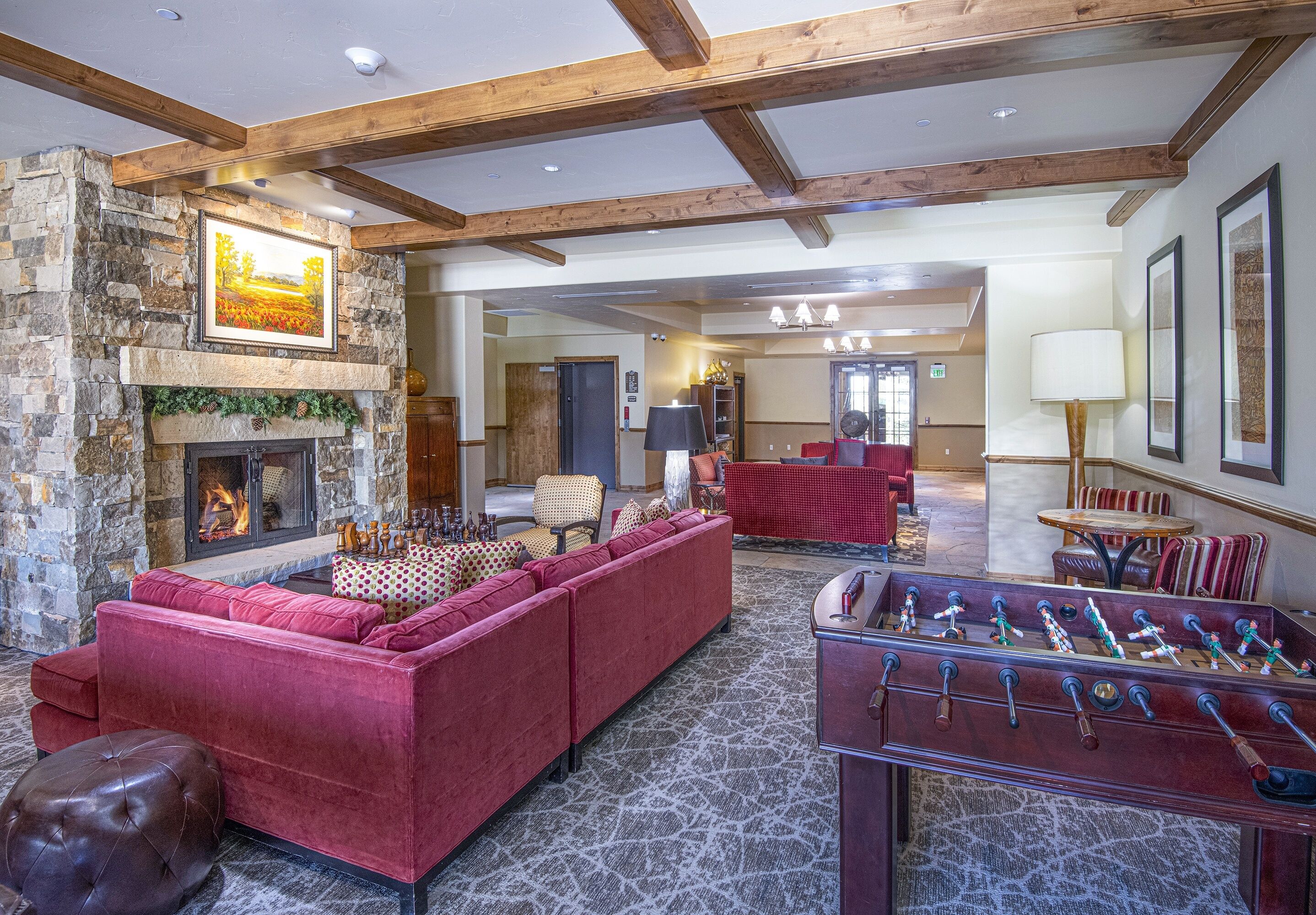 A spacious living room with a stone fireplace, red sofas, and a foosball table.