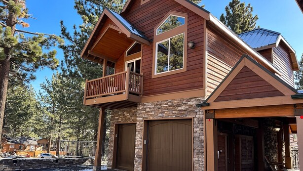 A two-story log cabin with a balcony, stone foundation, and a garage. - Mammoth Gateway Village #6 3 Bedroom Condo by RedAwning (Mammoth Lakes)