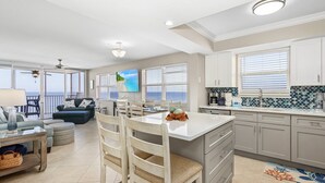 A spacious living area with a large island, dining chairs, and a view of the ocean. - Beach Villas # 506-250 Estero Blvd 2 Bedroom Apts by RedAwning (Fort Myers Beach)
