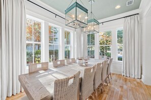 Enjoy meals in this dining area with a long table and wicker chairs.