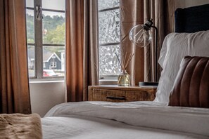 A bedroom with a bed, a nightstand, a lamp, and a window with curtains.
