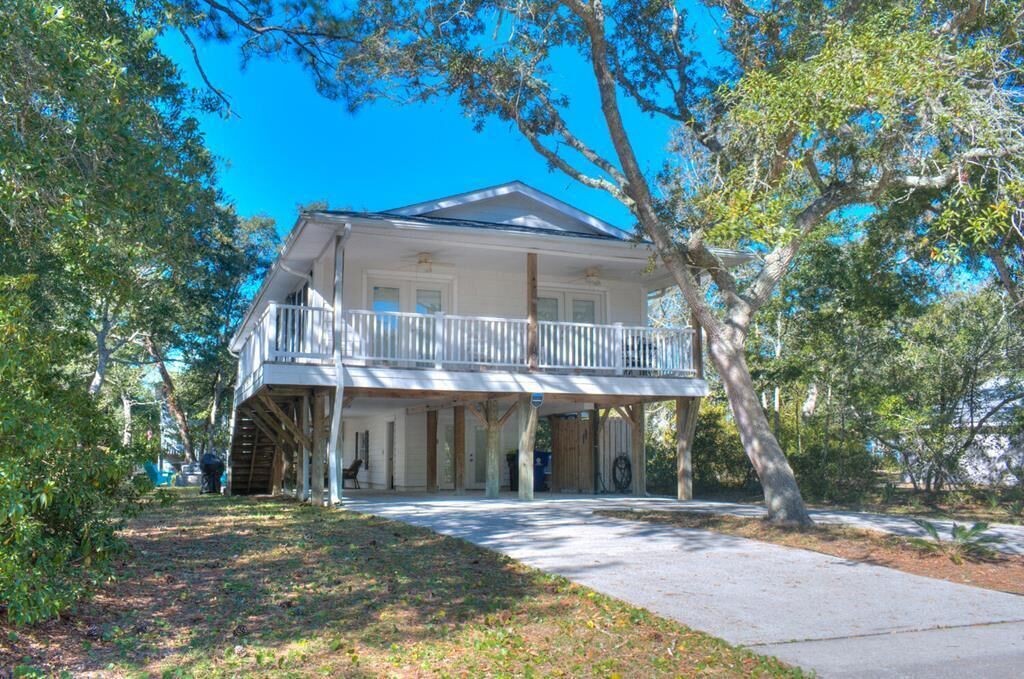 A two-story house with a balcony, surrounded by trees and a clear sky.
