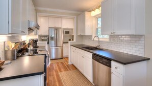 Una cucina moderna con mobili bianchi, elettrodomestici in acciaio inossidabile e un piano di lavoro nero.