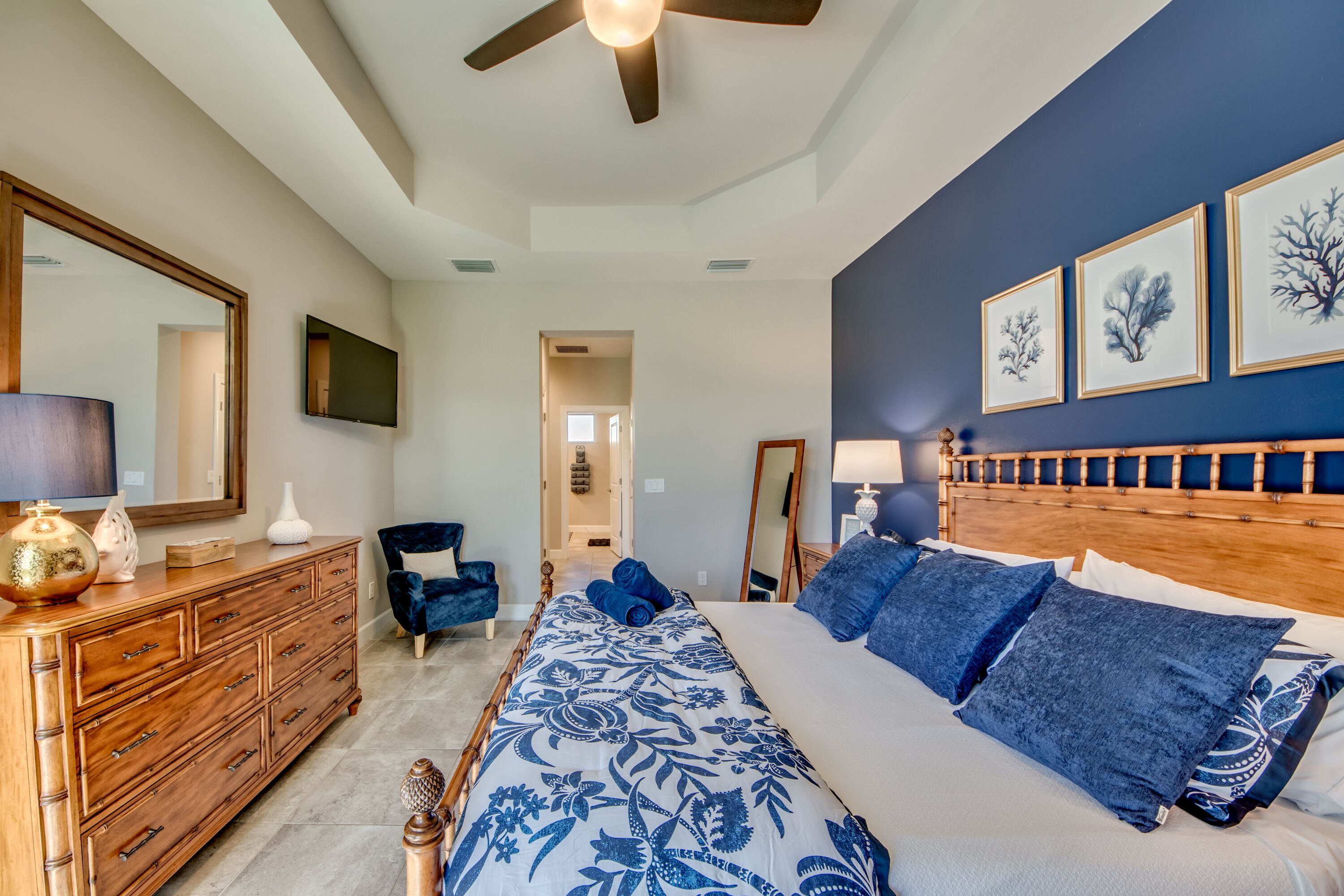 Ein Schlafzimmer mit einem großen Bett, einer Holzkommode, einem Stuhl und einem Deckenventilator.