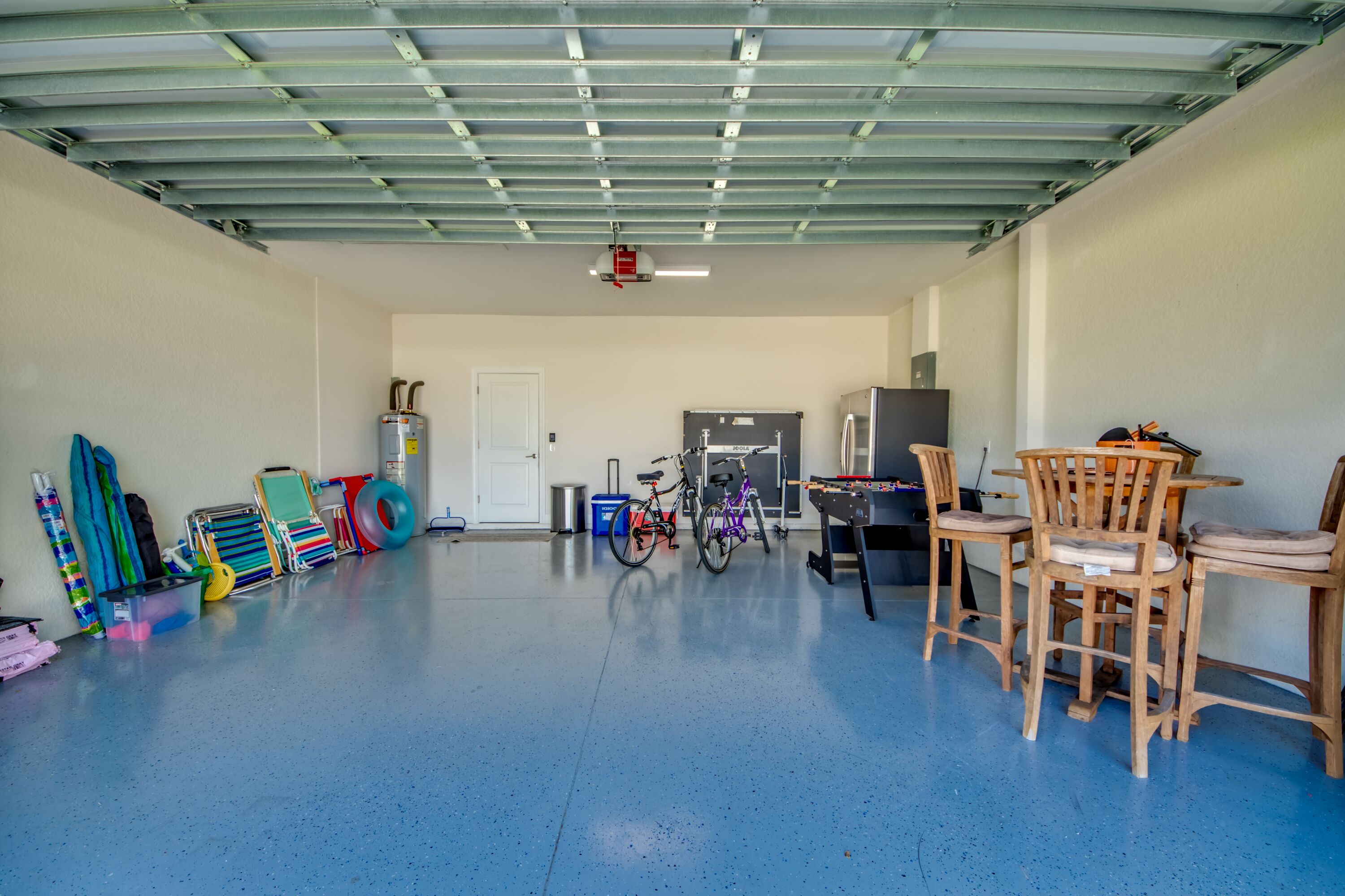 A spacious garage with a blue floor, a door, and a table with chairs.