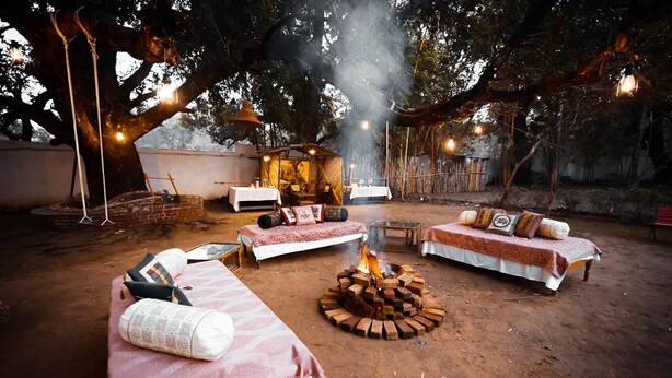 An outdoor seating area with sofas and a central fire pit. - Rosewood Resort (Bichhiya)