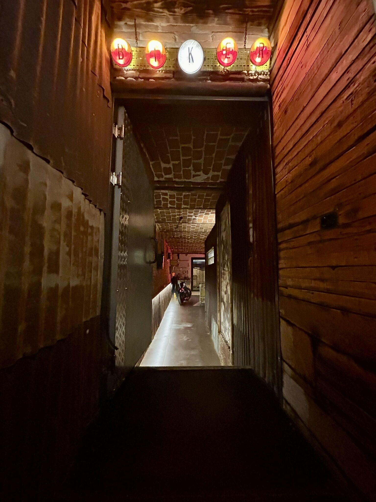 A narrow corridor with wooden walls and a tiled ceiling.