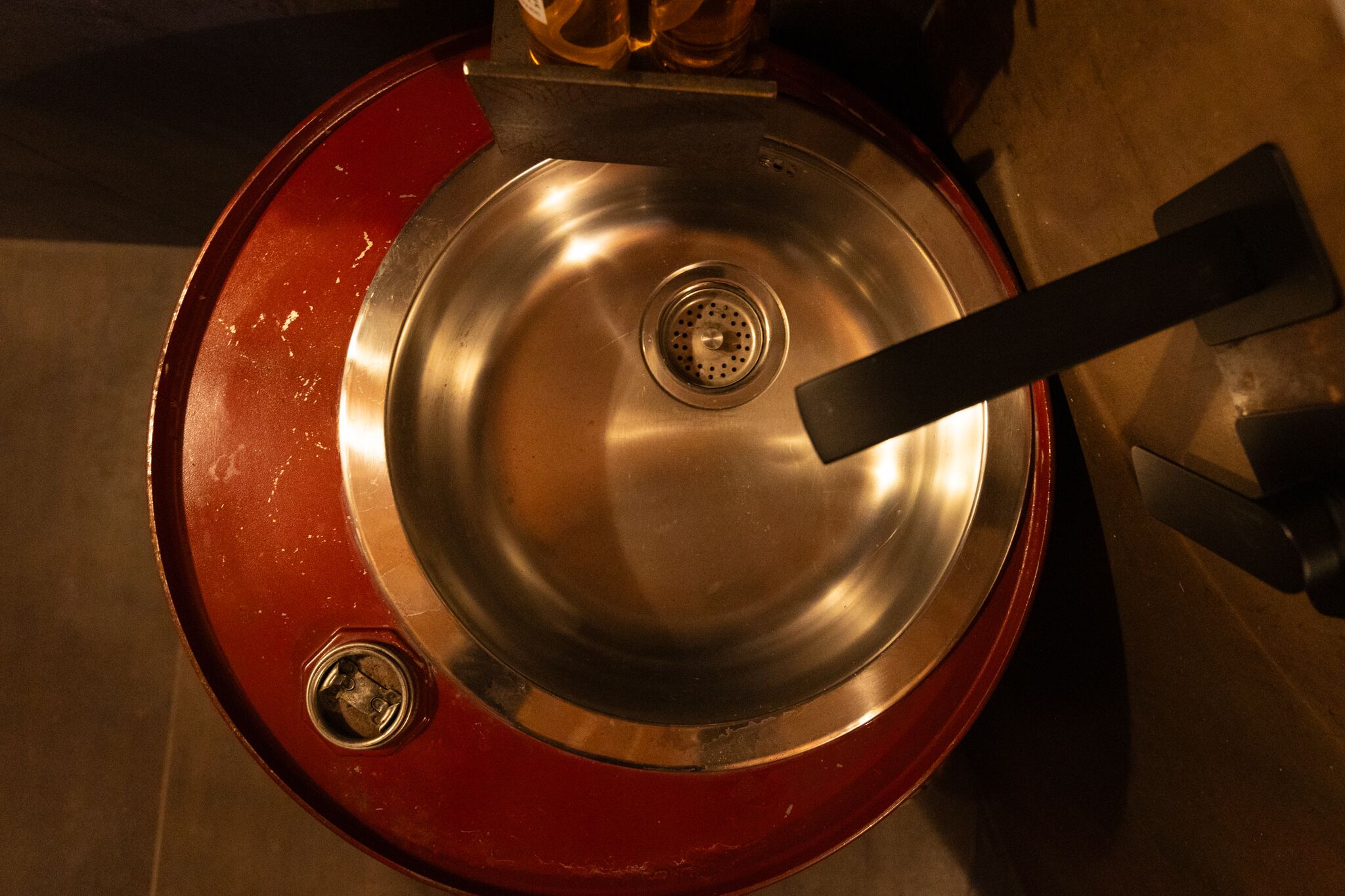 A metallic sink with a drain and a faucet.