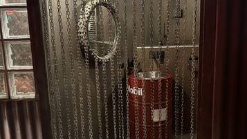 A room with a chain-link curtain, a circular mirror, and a red barrel.