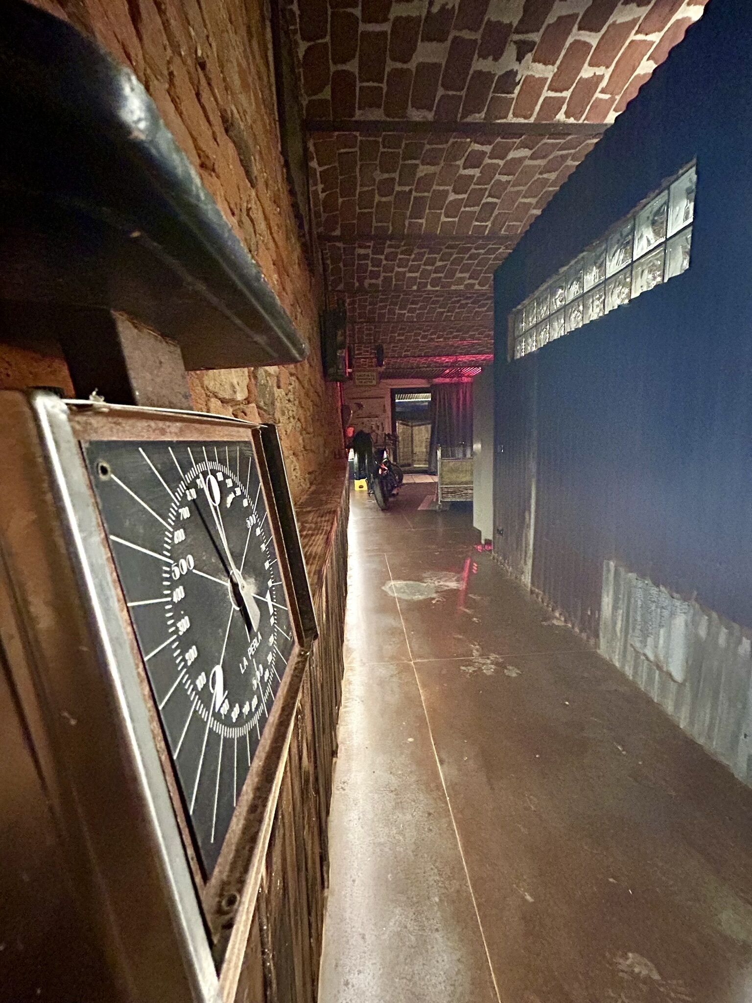 Un corridoio con un orologio a sinistra, un soffitto piastrellato e un pannello decorativo sulla parete.