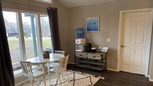 A room with a dining table and chairs, a coffee maker, a water dispenser, and a welcome sign.