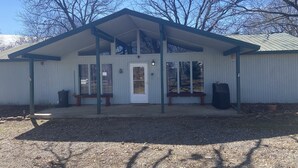 A single-story building with a gabled roof, a front door, and a bench outside.