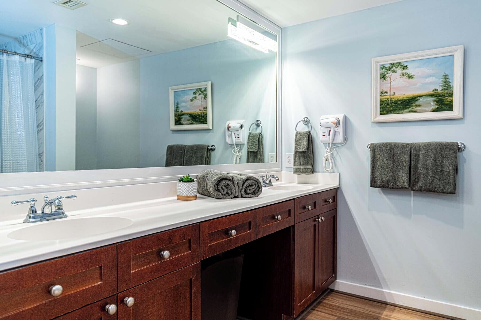 A bathroom with a large mirror, a sink, a towel rack, and a hairdryer.