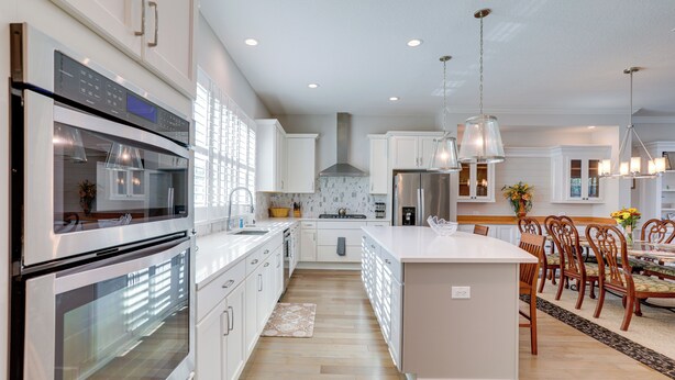 A modern kitchen with stainless steel appliances, white cabinetry, and a central island with seating. - Steps to Shore: Modern Redington Beach Townhome (Redington Beach)