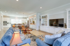 A spacious living room with a blue sofa, a wooden coffee table, and a television on a white cabinet. - Steps to Shore: Modern Redington Beach Townhome (Redington Beach)