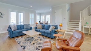 A spacious living room with a blue sofa set, a wooden coffee table, and a brown leather armchair. - Steps to Shore: Modern Redington Beach Townhome (Redington Beach)