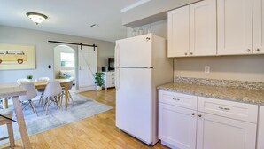A modern kitchen with white cabinets, a granite countertop, and a built-in refrigerator.