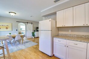 A modern kitchen with white cabinets, a refrigerator, a dining area with a table and chairs, and a plant. - 3 Mi to Riverwalk: Pet-friendly Home w/ Yard! (Palmetto)