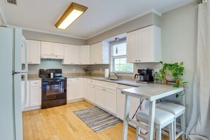 A modern kitchen with white cabinets, a stainless steel oven, a coffee maker, and a window providing natural light. - 3 Mi to Riverwalk: Pet-friendly Home w/ Yard! (Palmetto)