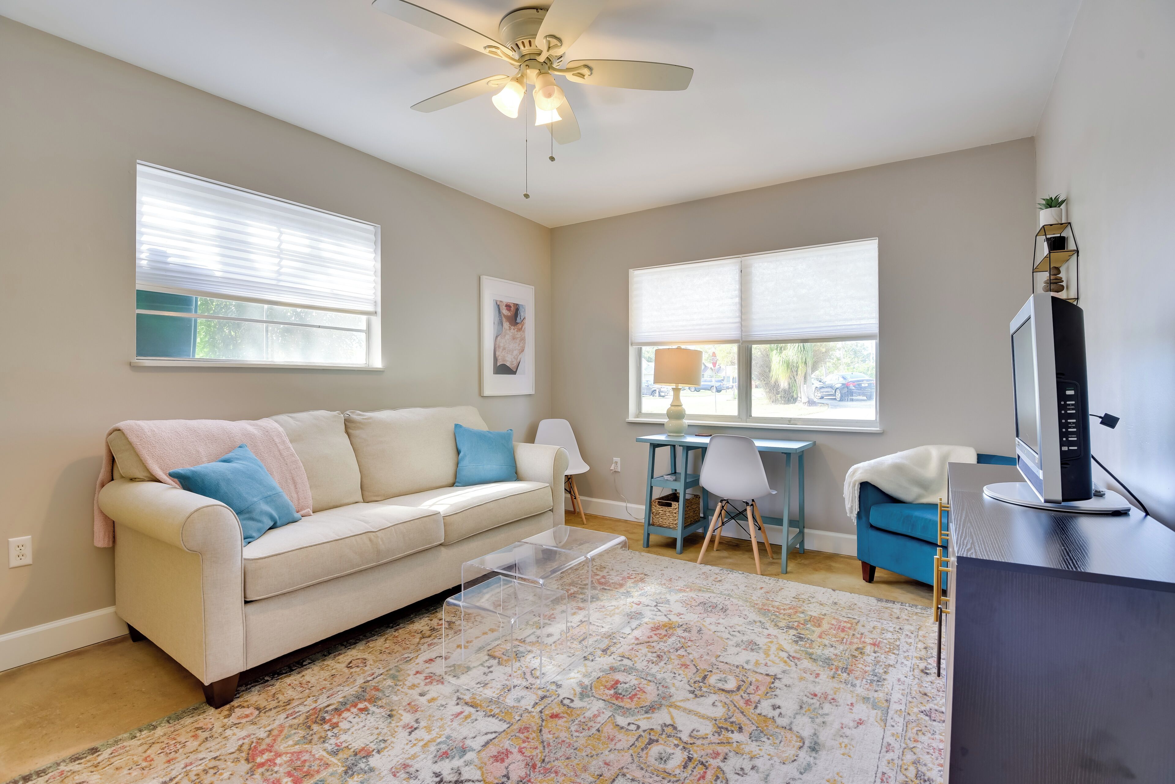 A living room with a beige sofa, a coffee table, a TV, and a ceiling fan.