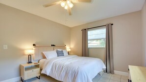 A bedroom with a bed, nightstand, lamp, and a ceiling fan.