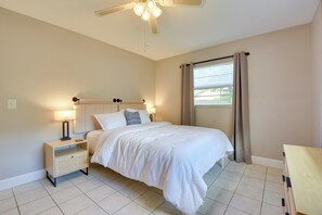 A bedroom with a bed, nightstand, lamp, ceiling fan, window with curtains, and a view of greenery outside. - 3 Mi to Riverwalk: Pet-friendly Home w/ Yard! (Palmetto)