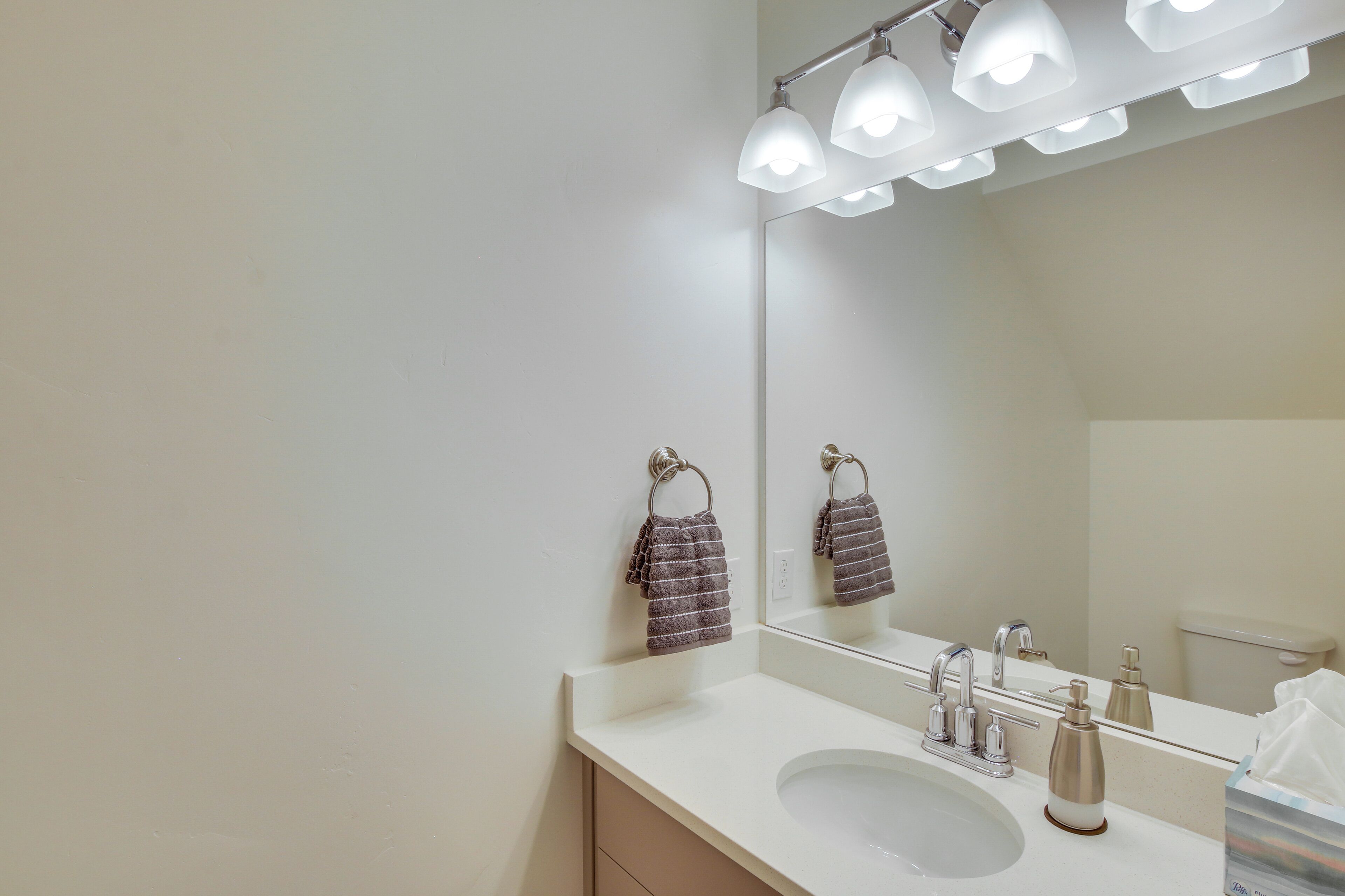 A bathroom with a white sink, a mirror, and a towel hanging on a hook.