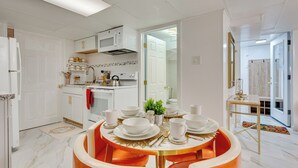 A modern kitchen with white cabinetry, a microwave, and a dining area with a round table and orange chairs. - 1 Mi to Downtown: Salem Vacation Rental! (Salem)