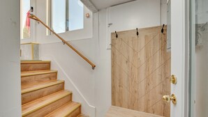A staircase with wooden steps and a handrail, leading to a room with a wooden door and a small window. - 1 Mi to Downtown: Salem Vacation Rental! (Salem)