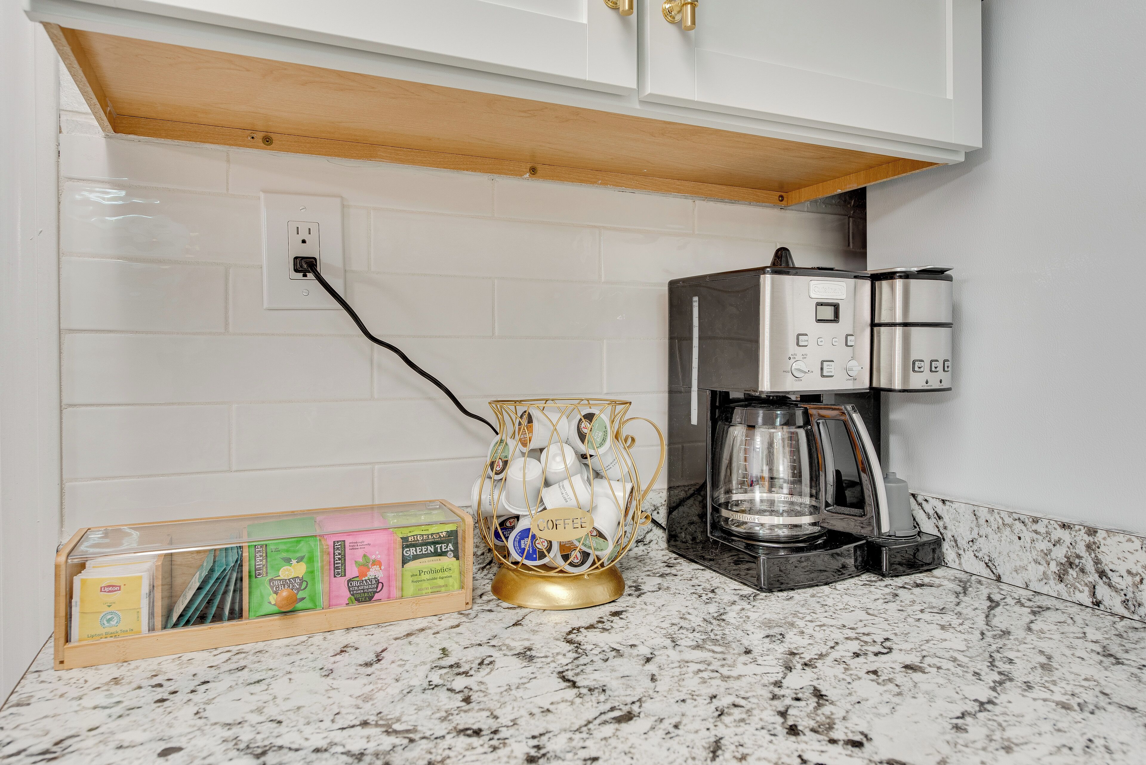 Una cocina con cafetera, un portavasos para tazas de café y una caja de té.