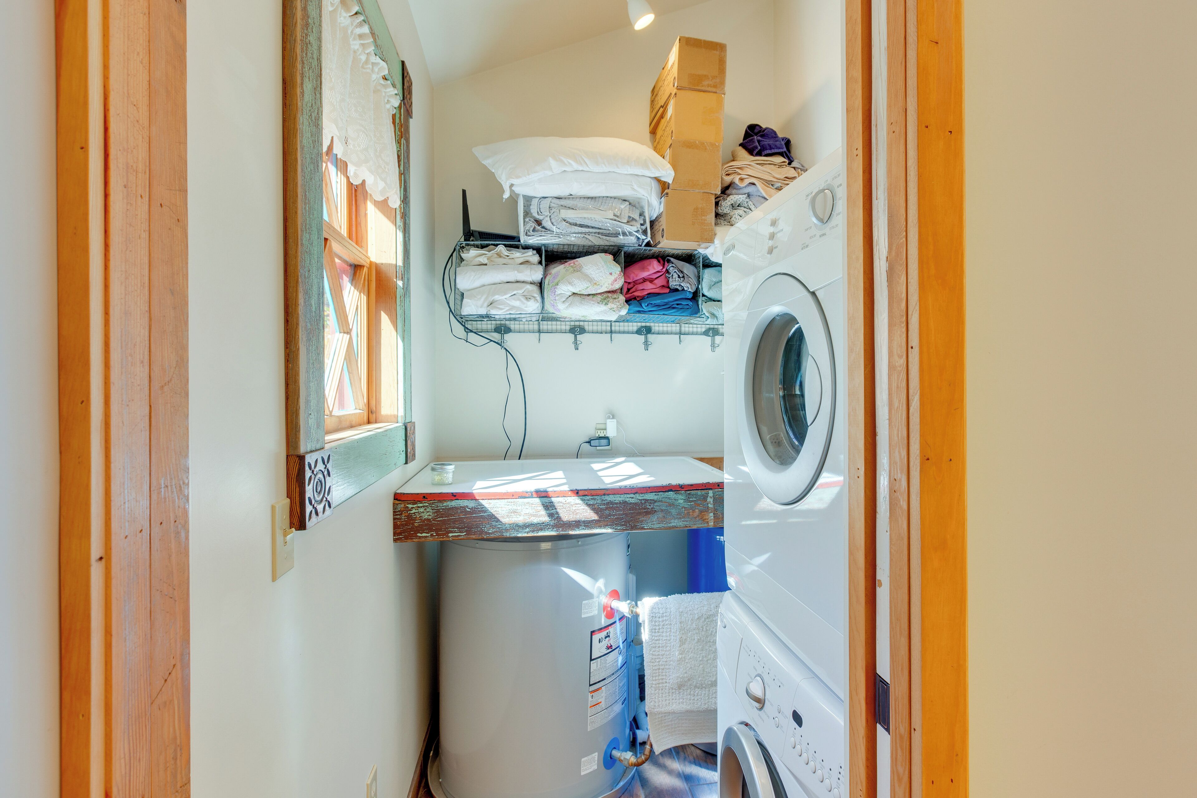 Une buanderie équipée d’un lave-linge, d’un sèche-linge et de piles de linge plié rangées sur des étagères.