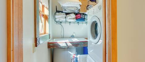 Une buanderie équipée d’un lave-linge, d’un sèche-linge et de piles de linge plié rangées sur des étagères.