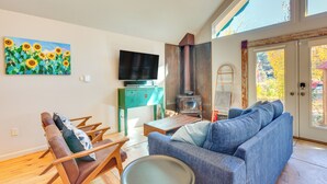 Een woonkamer met een bank, stoelen, een televisie, een schilderij en een open haard.