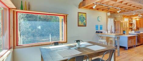 A dining area with a wooden table, chairs, and a view through a large window.