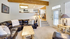 Ein Wohnzimmer mit einem schwarzen Ledersofa, einem Holztisch und einer Lampe.